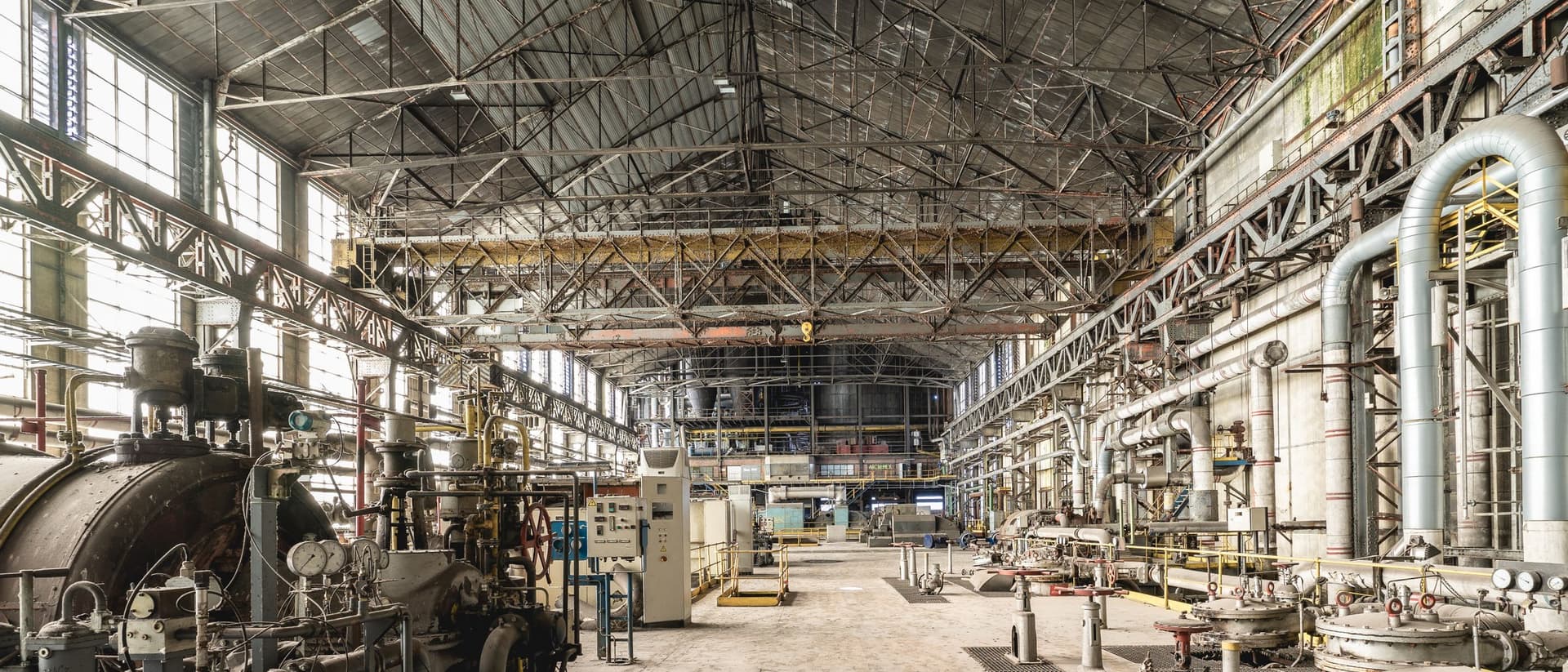 Interior de planta de processo com máquinas e rede de tubulações